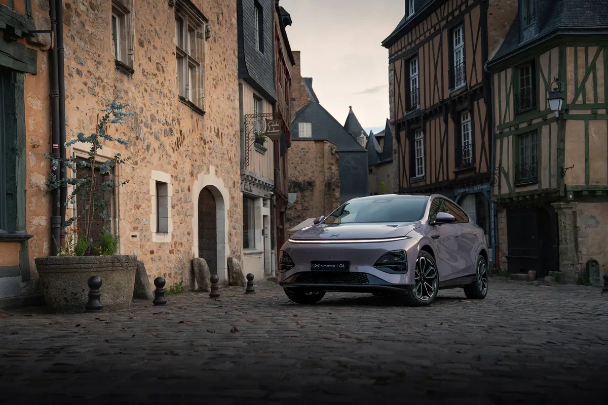 Grey XPENG G6 parked in a narrow historic street