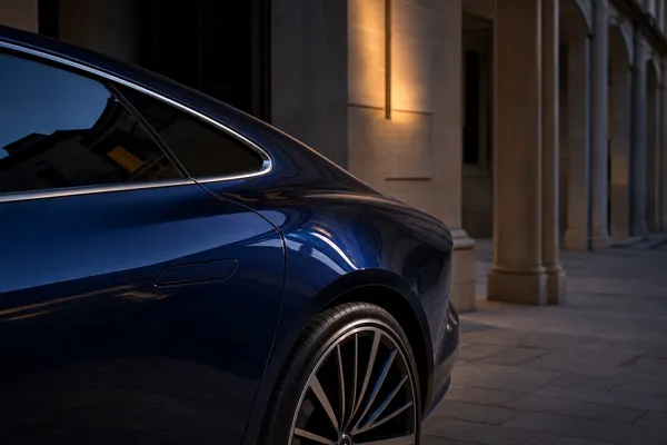 Close detail of a midnight-blue prestige vehicle beside limestone architecture