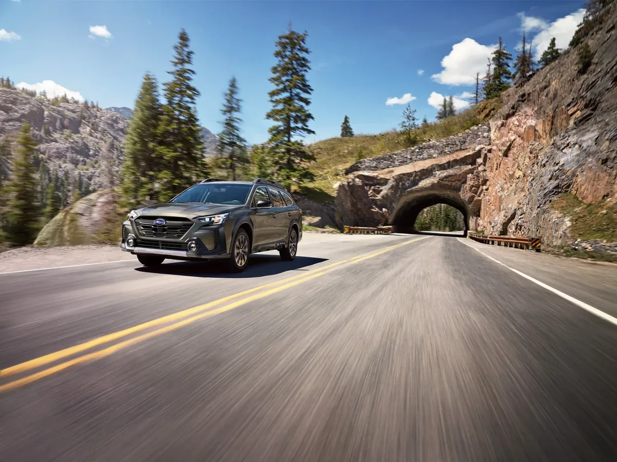 Black Subaru Outback driving through a rocky mountain pass