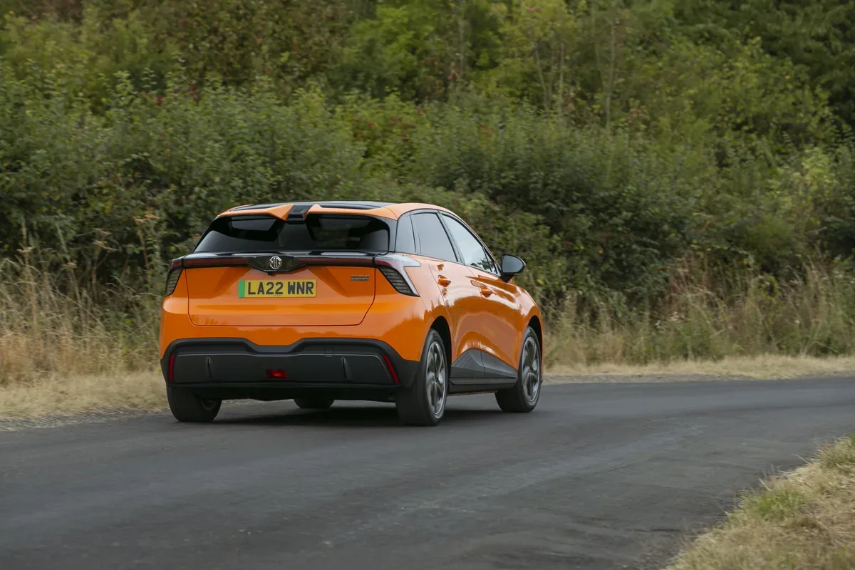 Orange MG4 EV driving away on a country road