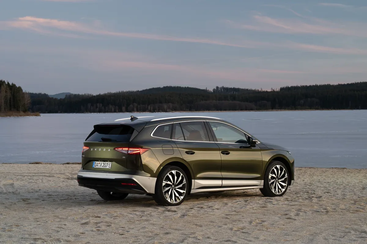 Green Skoda Enyaq parked beside a lake at dusk