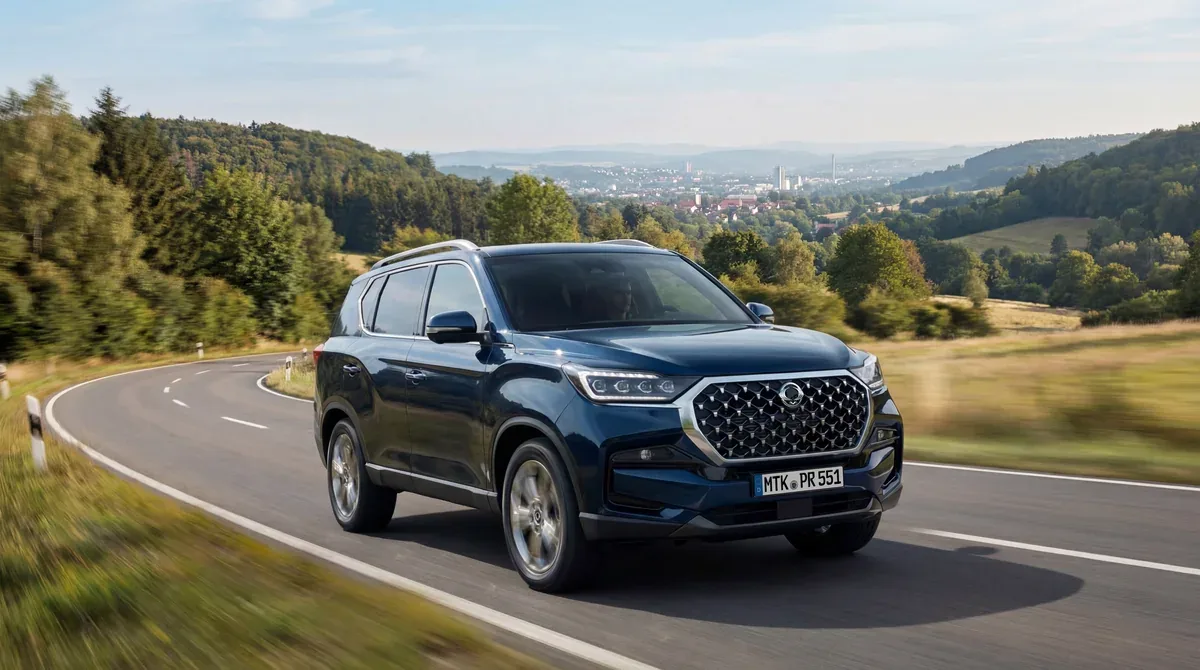 Blue KGM Rexton driving on a winding country road