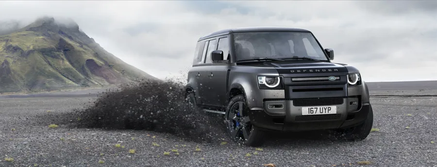 Land Rover Defender 110 in dark grey driving on a volcanic gravel landscape